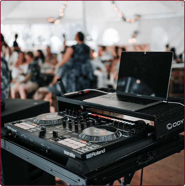 A dj 's laptop and mixer on top of a table.