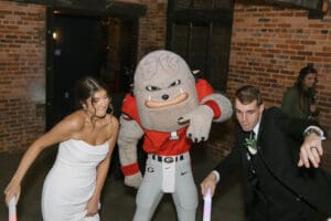 A bride and groom pose with an ohio state mascot.