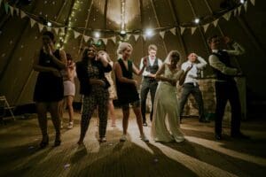 People dancing and enjoying a lively party under string lights.