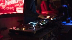 DJ mixing music on turntables in a dimly lit club.