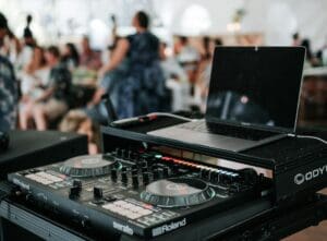 DJ equipment setup at a lively party with people dancing in the background.