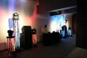 DJ performing in a dimly lit event space with colorful lighting.